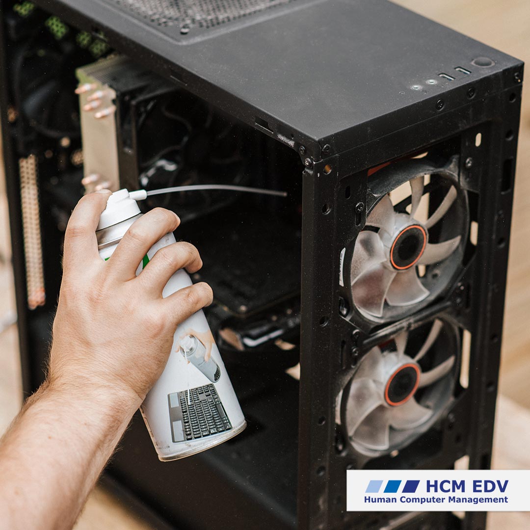 Ein Mann, der das Innere eines Computers mit einer Druckluft-Spraydose von Staub reinigt